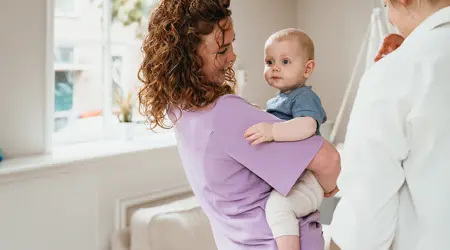 Moeder houdt baby vast op kinderopvang