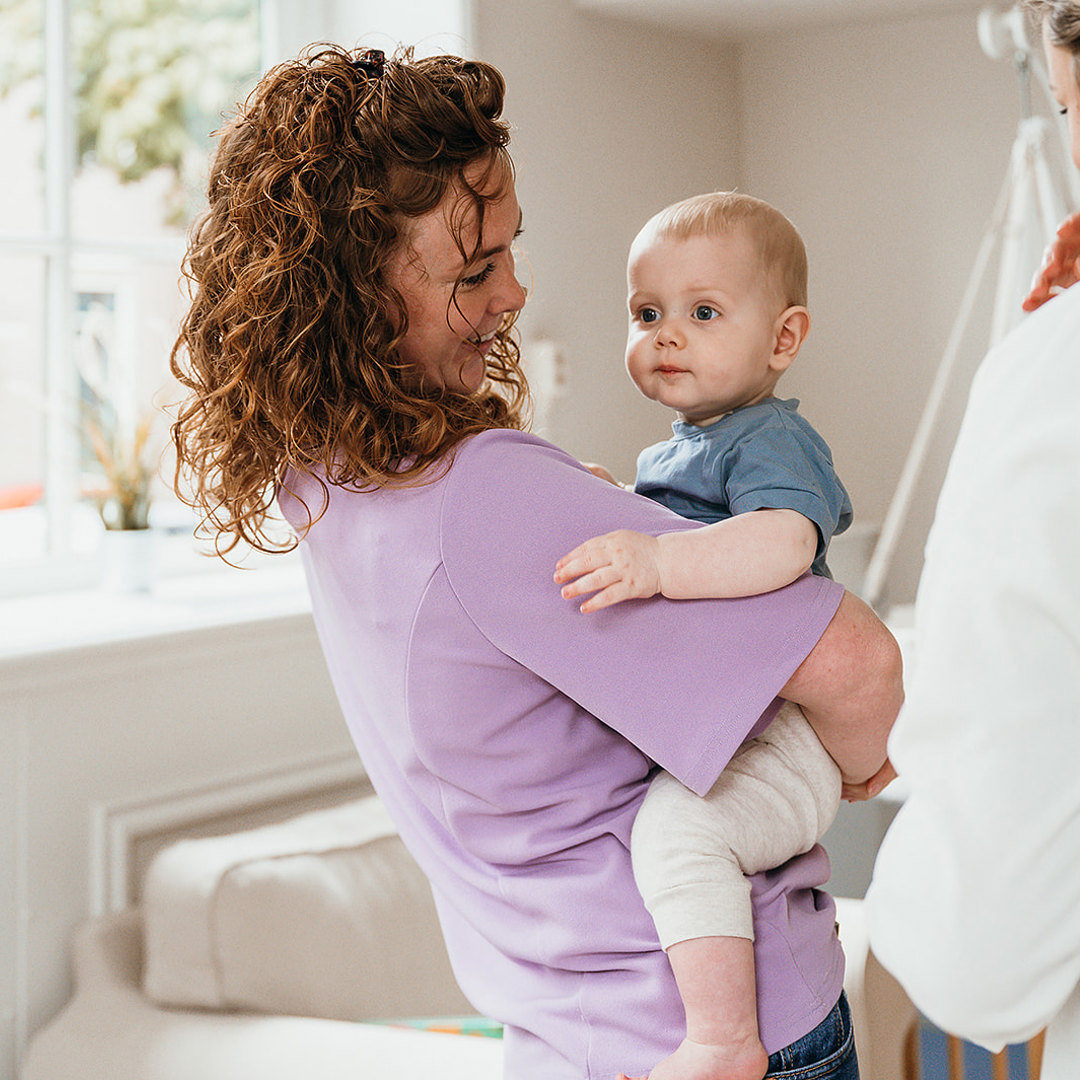 Moeder houdt baby vast op kinderopvang
