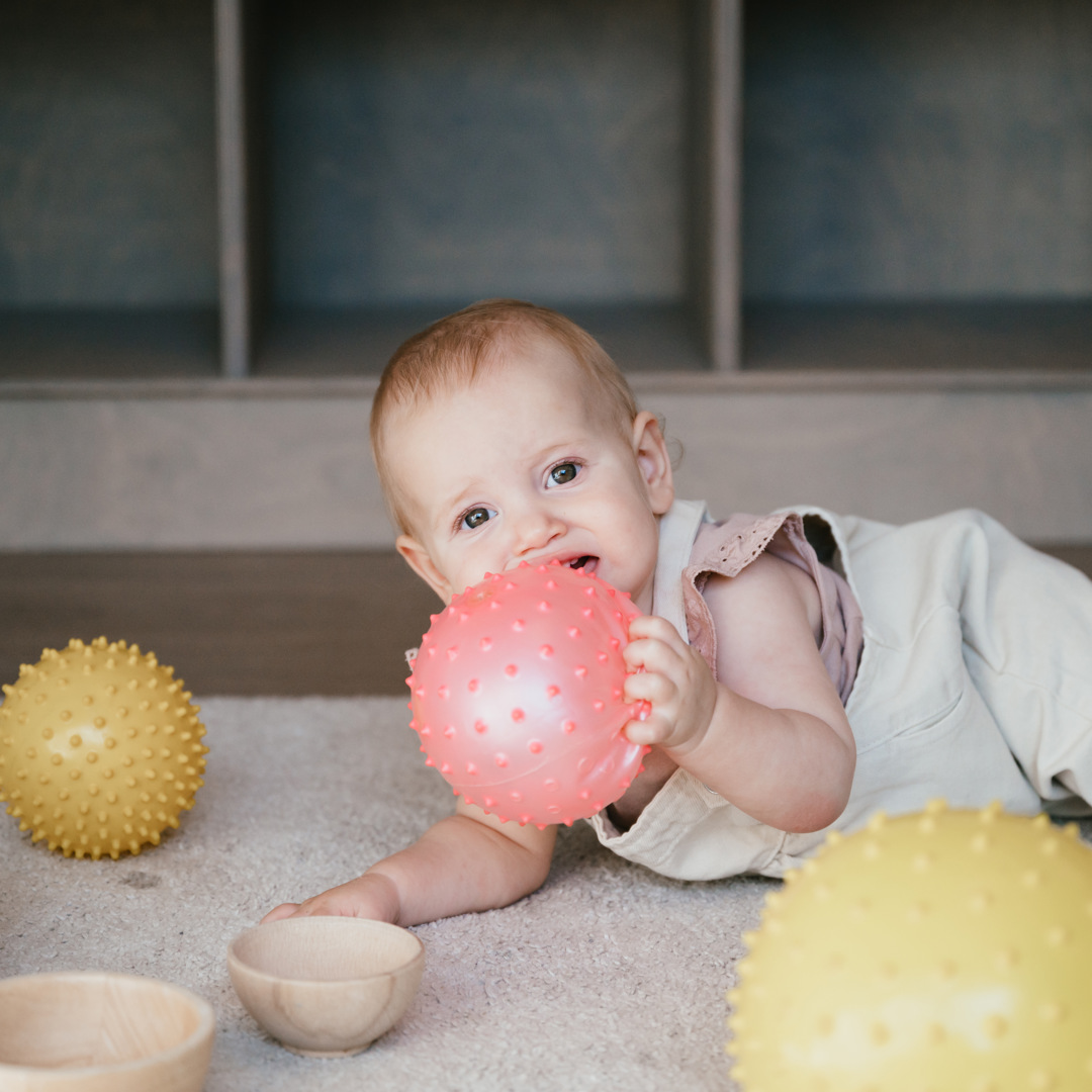 Baby speelt op kinderopvang op grond met bal