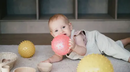 Baby speelt op kinderopvang op grond met bal