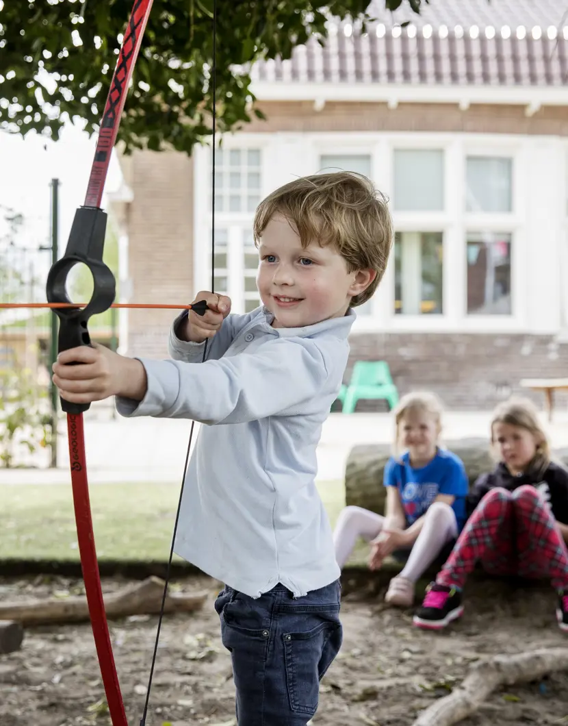 jongen speelt in tuin met pijl en boog