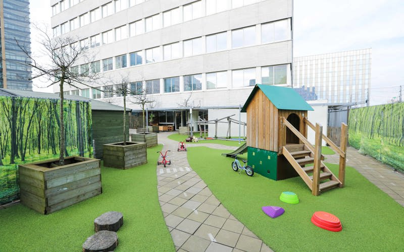 buiten speelruimte van kinderopvang met een grasveld, fietsbaan en speeltoestel