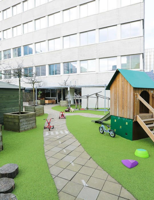 buiten speelruimte van kinderopvang met een grasveld, fietsbaan en speeltoestel