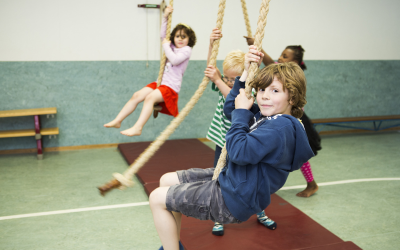 kinderen hangen aan touwen in gymzaal
