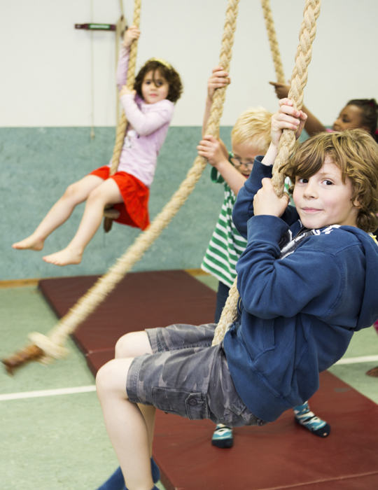 kinderen hangen aan touwen in gymzaal