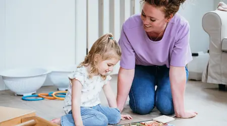 Meisje en vrouw doen samen een puzzel op de grond