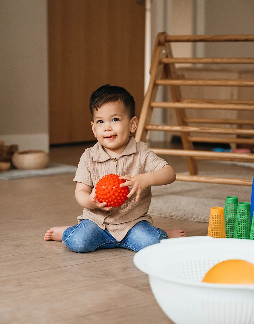 Jongetje zit op de grond en speelt met bal