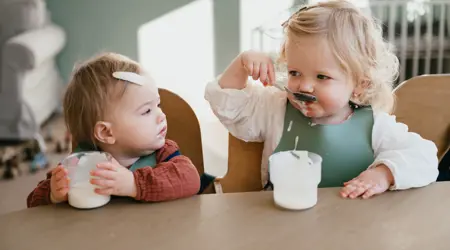 Twee kinderen eten yoghurt aan tafel