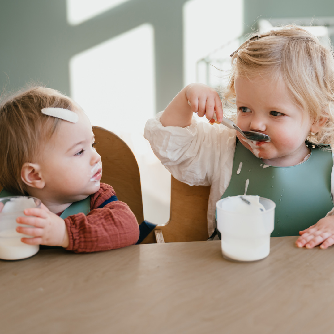 Twee kinderen eten yoghurt aan tafel