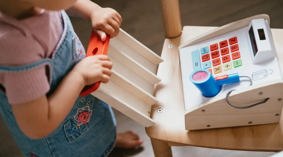 kind speelt met houten speelgoed kassa