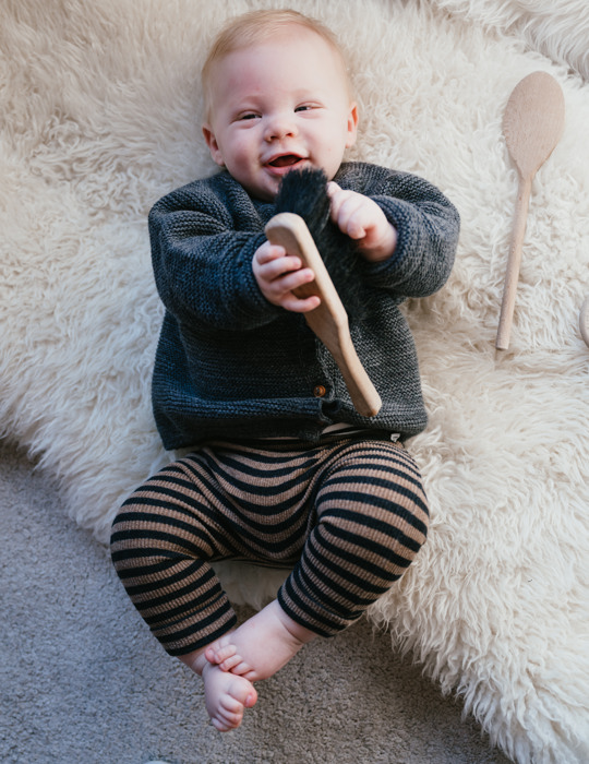baby ligt op kleed en kijkt blij